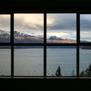 calm body of water near brown mountain under white and gray sky
